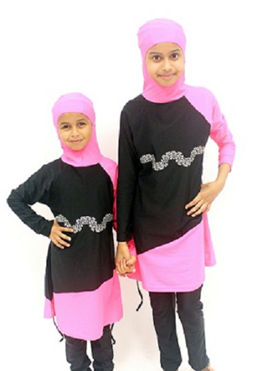Two children wearing matching black and pink swimsuits with attached hoods
