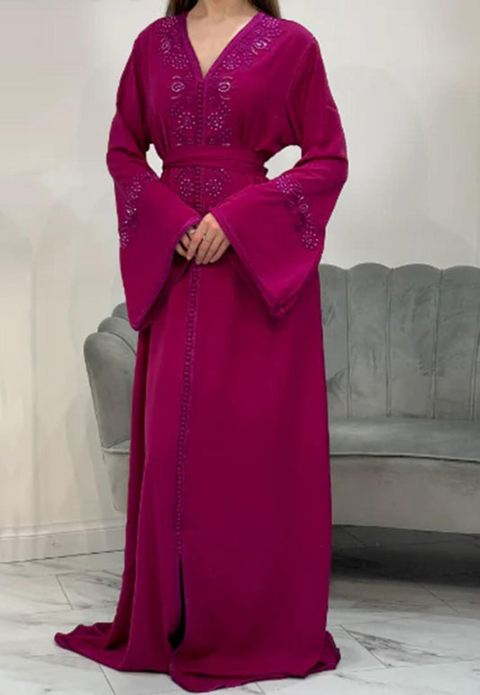 A woman wearing a pink full-length kaftan with embellishments on the neckline and sleeves